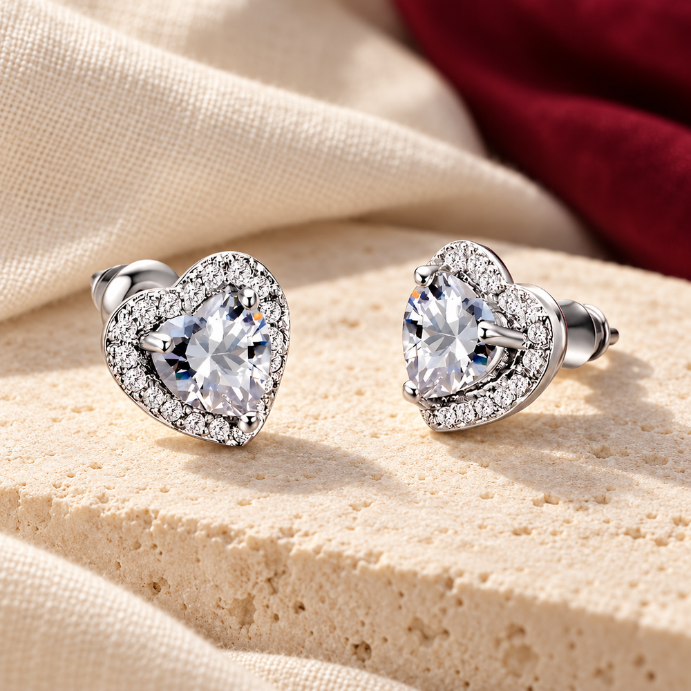 Silver-tone heart stud earrings on ivory stone with burgundy fabric